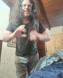 a man with long curly hair and glasses is standing in a room