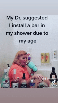 a woman is drinking from a cup while sitting in a bathtub surrounded by bottles of liquor .