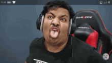 a man wearing headphones is sticking his tongue out while sitting in an dxracer chair