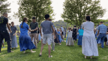 a group of people are dancing in a field with a man wearing a shirt that says ' i love you '