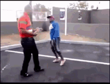 a man in a red shirt is talking to a man in a blue jacket while they are standing in a parking lot .