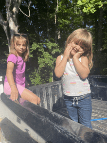 two young girls sitting in the back of a truck