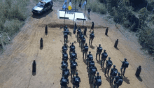 an aerial view of a group of soldiers standing in a line with a car parked in the background