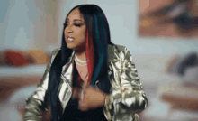 a woman with long black hair is wearing a gold jacket .