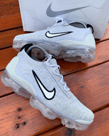 a pair of white nike vapormax shoes are sitting on a wooden table