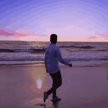 a man in a white shirt is walking on a beach