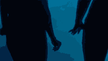 two people holding hands in the dark with a blue background