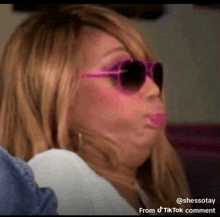 a woman wearing pink sunglasses is making a face