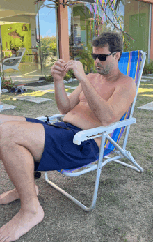 a shirtless man is sitting in a chair looking at his phone