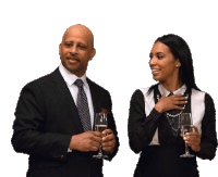 a man in a suit and tie stands next to a woman holding glasses of wine