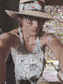 a woman wearing a hat and glasses is wearing a tank top with a sun and moon design