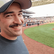 a man with a mustache is smiling in a baseball stadium with a logo for coca cola in the background