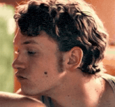 a close up of a man 's face with curly hair and a beard looking down .