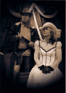 a man in a cowboy hat holds a gun next to a woman in a wedding dress