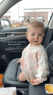 a baby is sitting in the back seat of a car with a chick fil a bag in the background