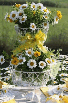 a stack of baskets filled with daisies and a yellow bow on top of each other on a table .