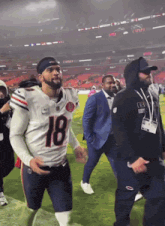 a football player with the number 18 on his jersey walks on the field