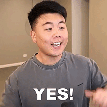 a man wearing a grey shirt with the words yes on it