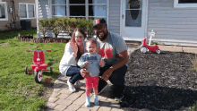 a family posing for a picture in front of a house with a little girl wearing a shirt that says vida