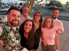 a group of people posing for a picture with a tree in the background