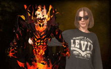 a person wearing a black levi 's shirt stands next to a fire monster