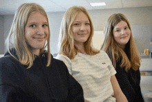 three girls are posing for a picture and one of them is wearing a levi 's shirt