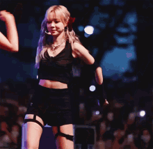 a woman in a black crop top and black shorts is dancing on a stage