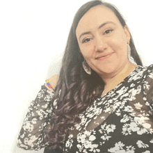 a woman is wearing a black and white floral shirt and earrings