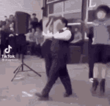 a man in a suit and tie is dancing in front of a crowd of people .