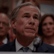 a man in a suit and tie is sitting in front of a microphone with the word fear behind him