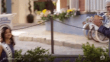 a man and a woman are standing next to each other on a sidewalk next to a chain link fence .