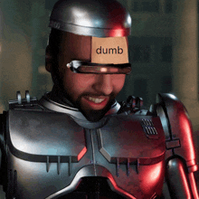 a man in a robot suit has a card on his face that says dumb