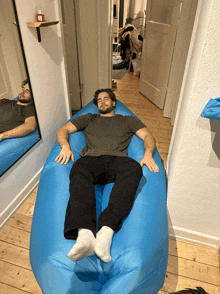 a man is laying on a blue bean bag chair