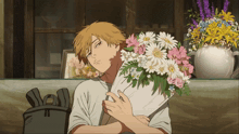 a man is holding a bouquet of flowers in front of a vase of flowers