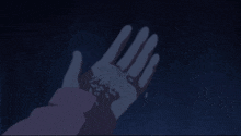 a person is holding something in their hand in a dark room .