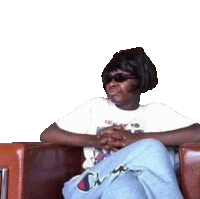 a woman is sitting on a couch wearing sunglasses and a white shirt .