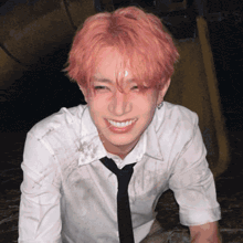 a young man with pink hair and a white shirt and tie smiles