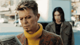 a man in a yellow sweater reads a newspaper that says mess showered us