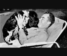 a black and white photo of a man petting his dog