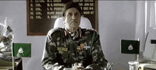 a man in a military uniform is sitting at a desk in front of a sign that says vijay barry