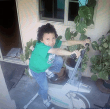 a young boy in a green shirt is riding a exercise bike