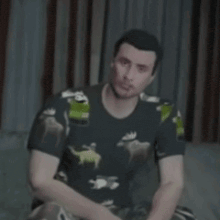 a man wearing a t-shirt with frogs on it is smiling and sitting on a couch .