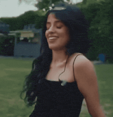 a woman in a black tank top is laughing in a park