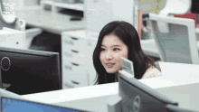 a woman is sitting at a desk in front of a computer monitor with the word twice on the bottom