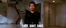 a man in a black shirt is standing in a room with stairs and says `` shit , shit , shit '' .