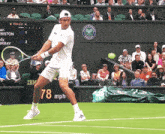 a tennis player is swinging a racket at a tennis ball in front of a scoreboard that reads 78 mph