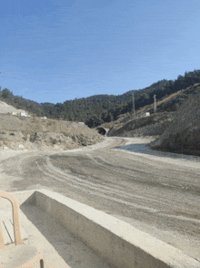 a dirt road going through a tunnel with a blue sky in the background