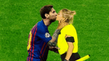 a soccer player is kissing a female referee on the cheek on a soccer field .