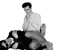 a black and white photo of a man sitting on another man 's back .