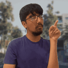 a man wearing glasses and a blue shirt points up